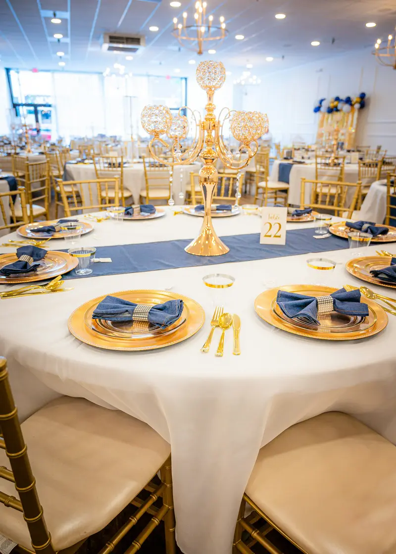 Festlich gedeckte Tafel mit goldenen Tellern und blauen Servietten